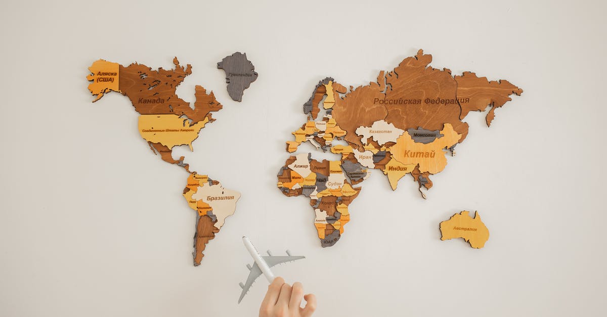 Is there another name for unrendered lard? - Crop unrecognizable person with toy aircraft near multicolored decorative world map with continents attached on white background in light studio