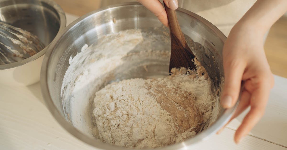 Is there any benefit to mixing bread dough by hand? - A Person Mixing the Dough Using a Wooden Spatula in a Stainless Bowl