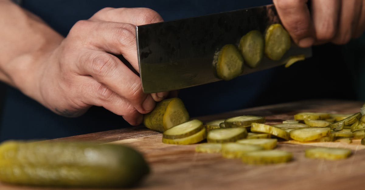Is there any danger slicing pickles hours before frying them? - Person Slicing Pickles on a Wooden Chopping Board