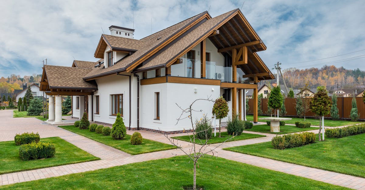 Is there any difference between cheap and expensive vodka? - Exterior of modern cottage house with columns and balcony surrounded by green grass and trees
