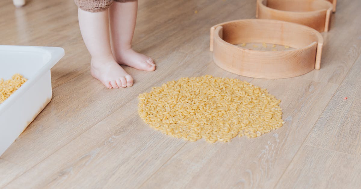 Is there any difference between wholewheat pasta and wholewheat sphaghetti besides the shape? - Crop faceless toddler standing barefoot on floor and playing with round wooden shapes of different size and pasta developing fine motor skills at home