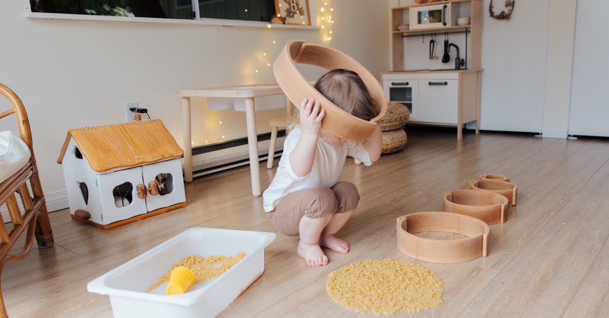 Is there any difference between wholewheat pasta and wholewheat sphaghetti besides the shape? - Full length of anonymous toddler squatting barefoot on floor playing with round wooden shapes of different size and pasta and putting biggest shape on while developing fine motor skills at home