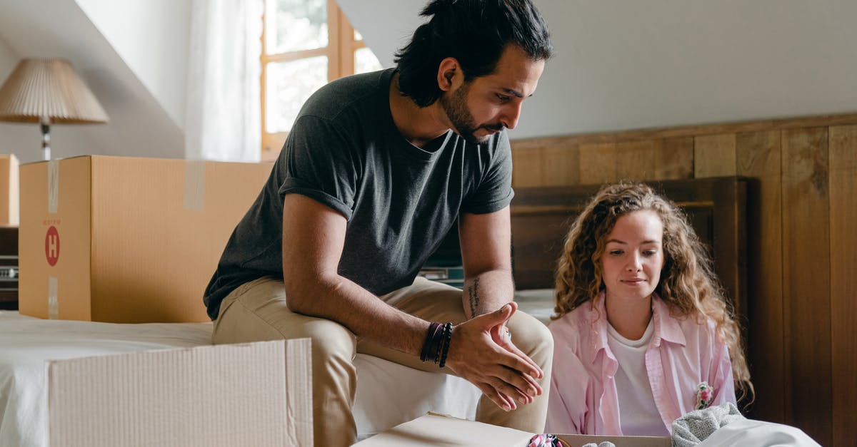 Is there such a thing as 'onion hair'? - Content adult ethnic man and woman in casual clothes sitting together in attic bedroom of new apartment among cardboard packages while unpacking stuff