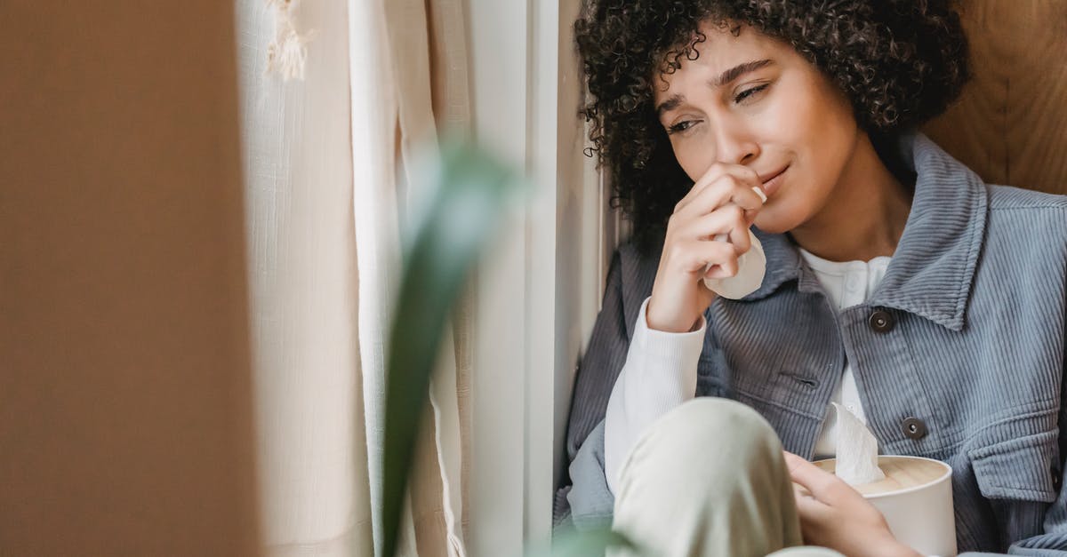 Is this a bad apple? - Sad African American female with tissue sitting on windowsill and crying while suffering from sorrow