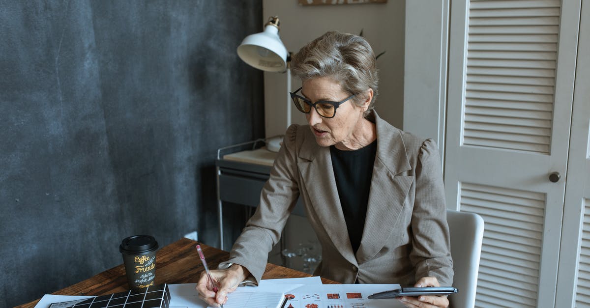 Is this coffee ratio calculation correct? - From above of concentrated senior female manager in formal outfit and eyeglasses taking notes in planner while working at table with various documents and takeaway coffee in cozy office