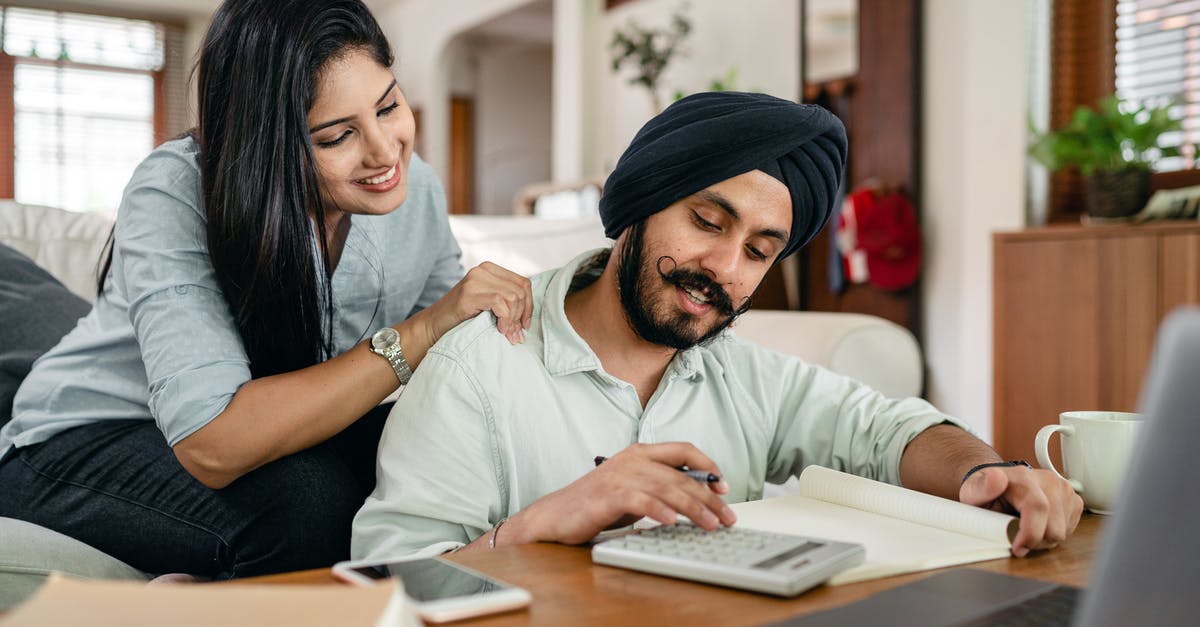 Is this coffee ratio calculation correct? - Smiling young Indian female in casual clothes supporting husband during remote work at home sitting in front of laptop with calculator notebook smartphone and cup of coffee at table