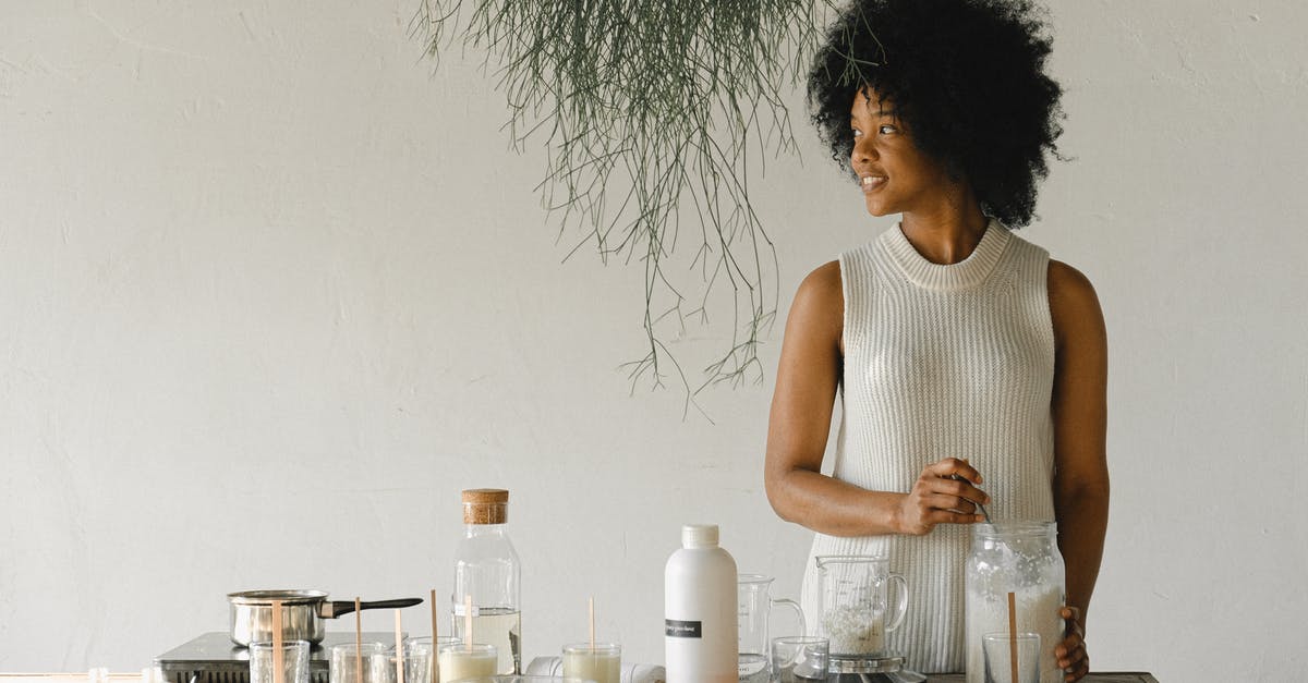 is this mold on my kimchi or yeast? - Content African American female artisan with jar of wax flakes looking away while creating candles in modern workshop in light room