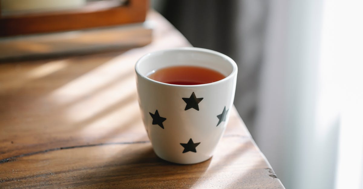 Is this white flaky powder in this tea "vanilla flavor"? - High angle of white ceramic cup with stars of hot tasty tea placed on wooden table