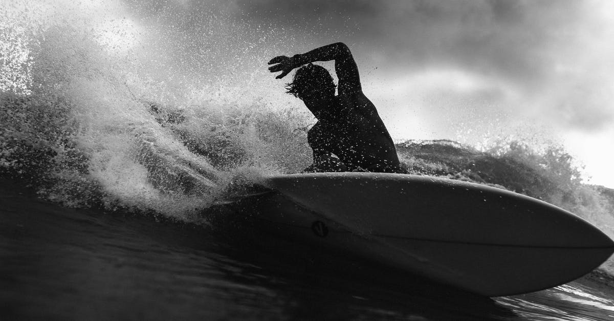 Is water on the outside of an electric kettle dangerous? - Black and white of anonymous male surfer riding on wave with raised arm against cloudy sky in stormy weather outside