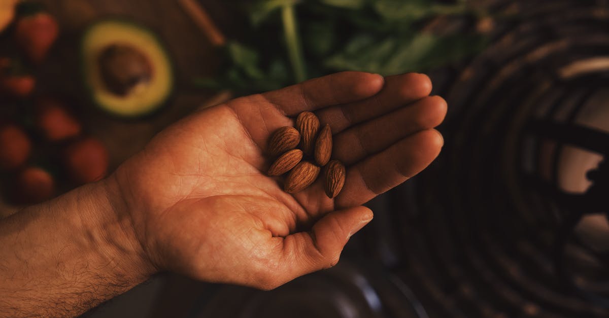 Is whole grain rye supposed to taste so coarse? - Top view of crop hand with pile of raw unpeeled almonds above table with ingredients