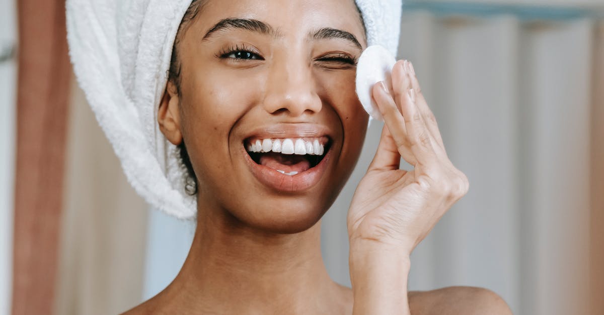 Japanese Cotton Sponge Cake - How to stop collapsing? - Delighted ethnic woman laughing brightly while looking at reflection and cleaning face with cotton pad in morning