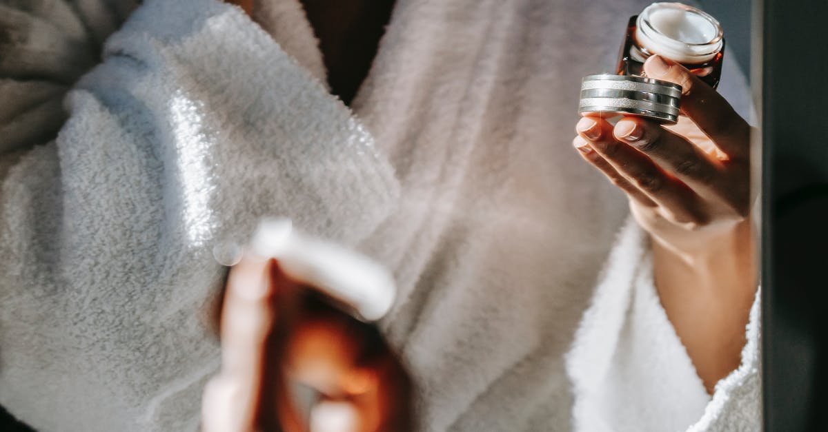 Jar lids popping several times - Crop ethnic woman with jar of cream against mirror