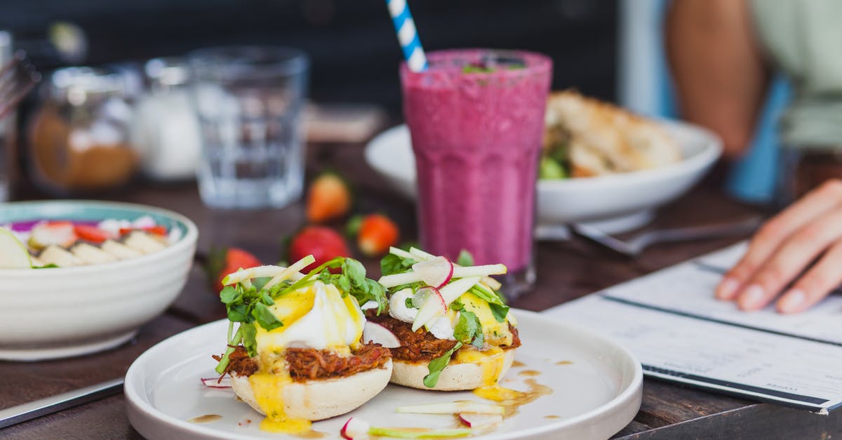 Juice recipe recommendation engine to give me recipes based on the ingredients I already have? - Appetizing sandwiches with poached eggs and sauce served with berry smoothie and placed on table with crop unrecognizable woman reading menu on background