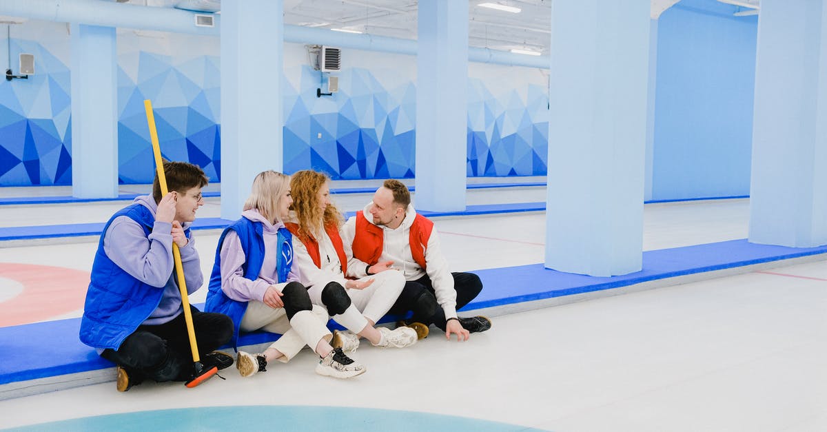 Keeping crushed ice from melting, without it joining back together - Sportsmen in red and blue waistcoats chatting on floor of spacious curling arena