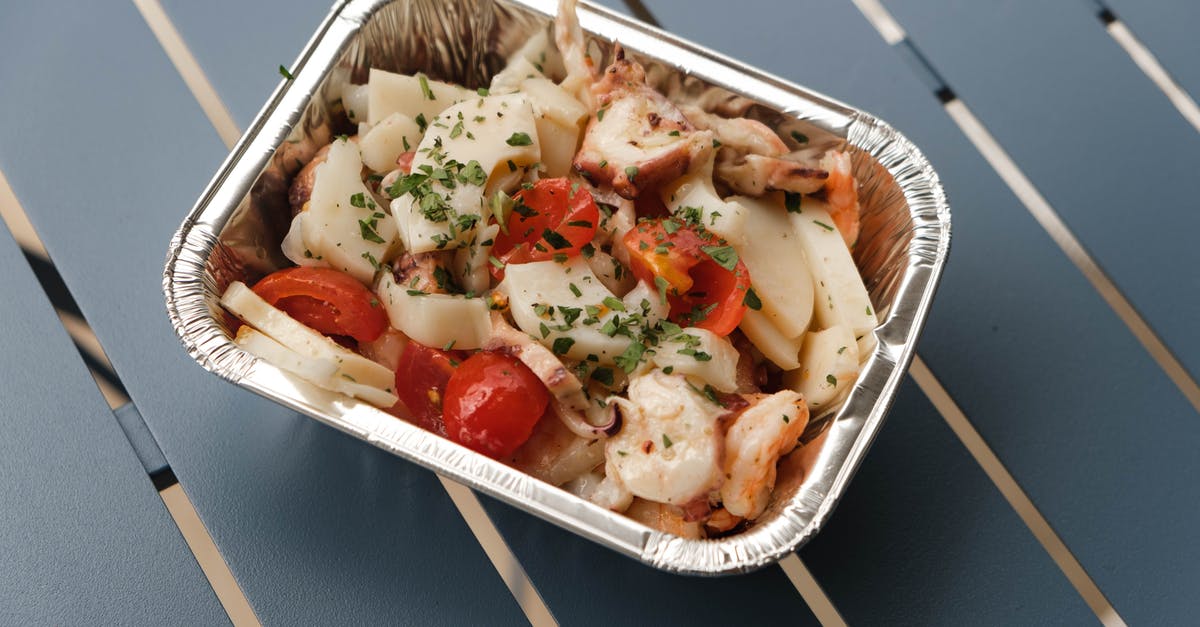 Keeping Hot Sauce From Separating - From above of tasty squids with tomatoes and herbs under sauce in foil container on blue metal table