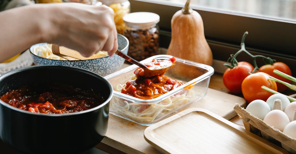 Key ingredients for classic Sauce Bolognese (Ragù Bolognese)? - Crop chef pouring bolognese on spaghetti