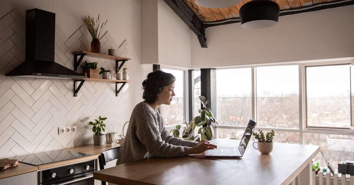 Kitchen clambake using kombu? - Side view of young female in casual clothes typing message on laptop while sitting at wooden table in kitchen