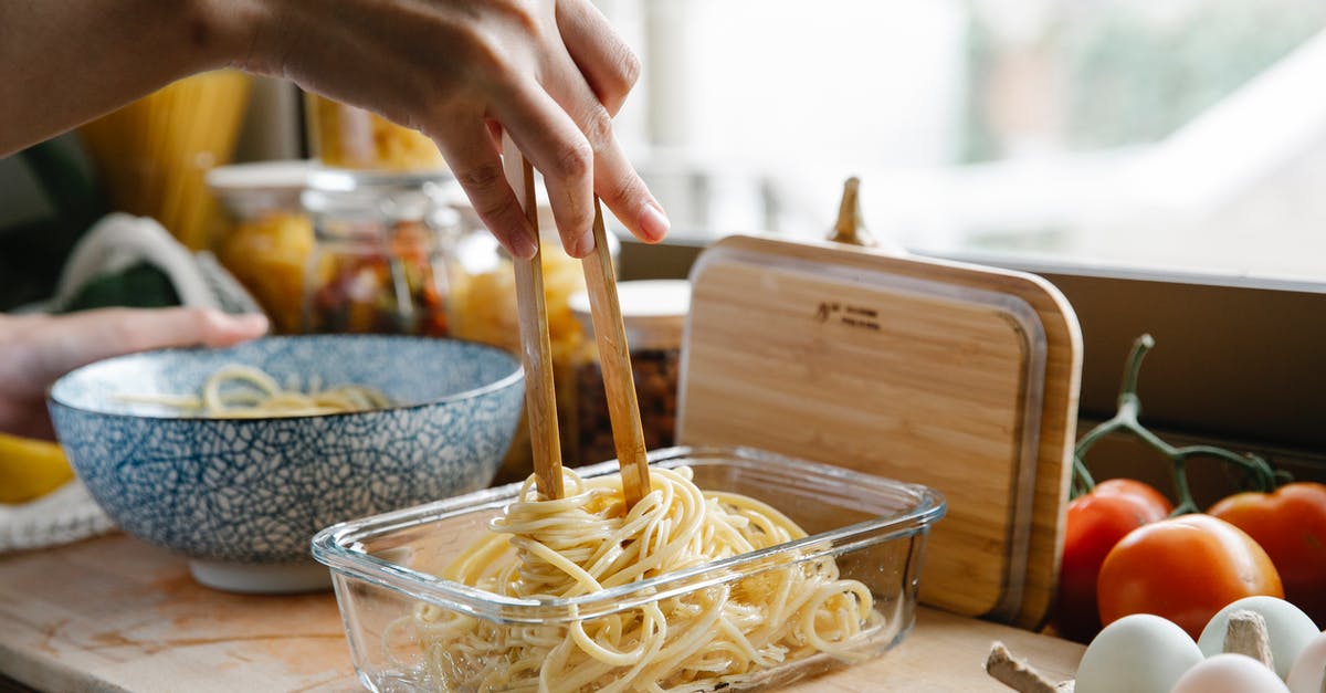 Kitchen utensil identification - tong of some sort - Unrecognizable female cook with tongs standing at counter with glass container of fresh pasta while cooking in kitchen on blurred background