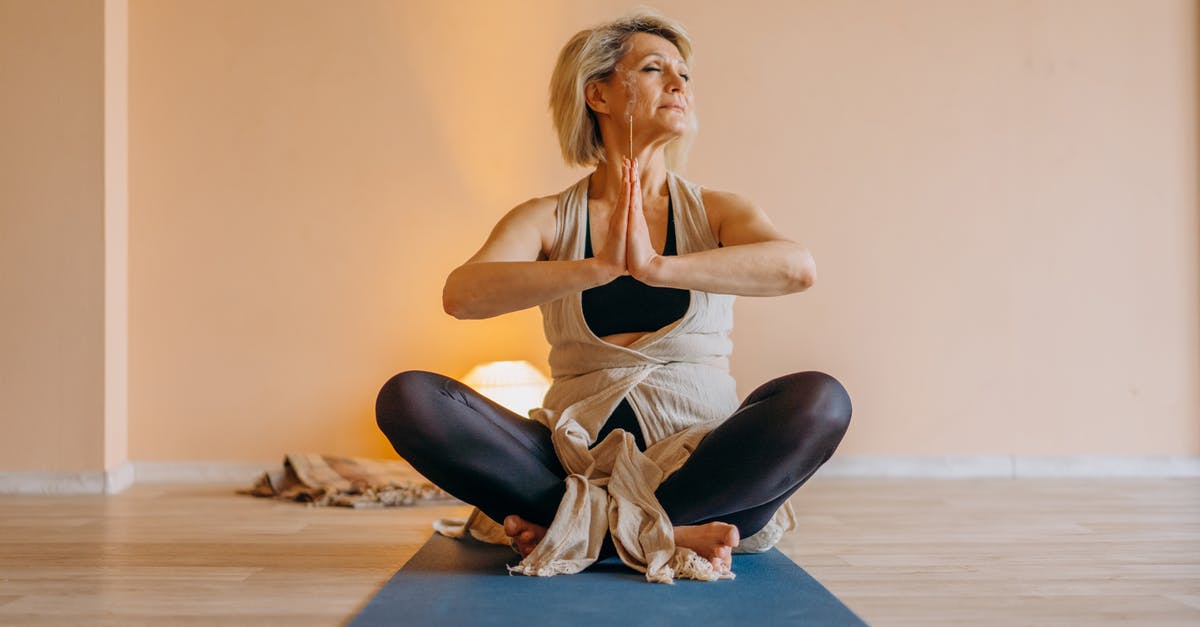 kneading vs. stretch and fold with pizza - Full body of middle aged lady in activewear sitting on mat in lotus position in light room with closed eyes