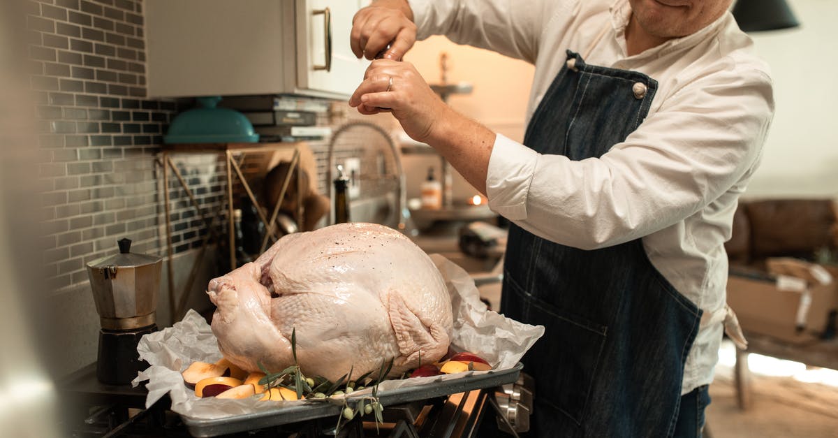 Know if a turkey is done cooking - Man in White Long Sleeve Shirt with Black Apron Preparing an Uncooked Turkey 