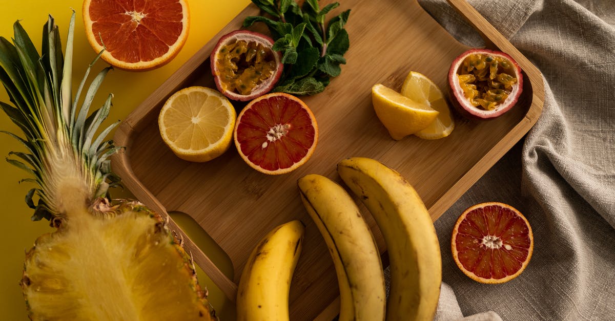 Lemon juice as a natural preservative for soups - High angle of cut pineapple and banana with halves of grapefruit and passion fruit and sliced lemon on wooden tray