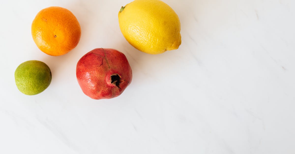 Lemon turned broccoli purple - From above of various colors ripe lime and tangerine and pomegranate and lemon placed on white table