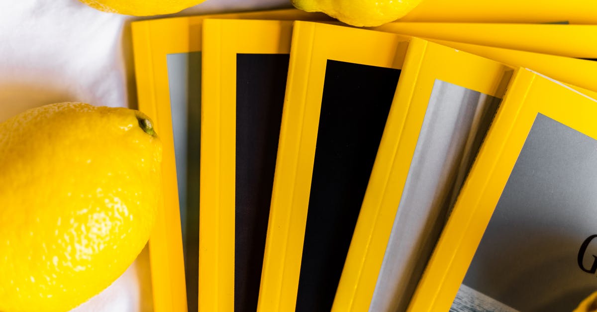 Lemon zest in large volumes - Top view of stack of similar books with yellow edges placed on white table near fresh whole lemons in daylight