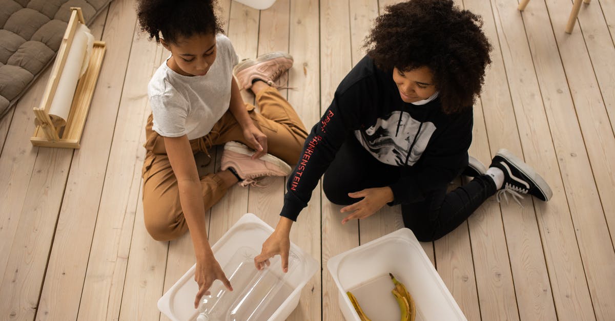 Lentils and barley used together - From above full body of African American mother and daughter sorting plastic bottles and banana peel into containers while sitting on wooden floor in room