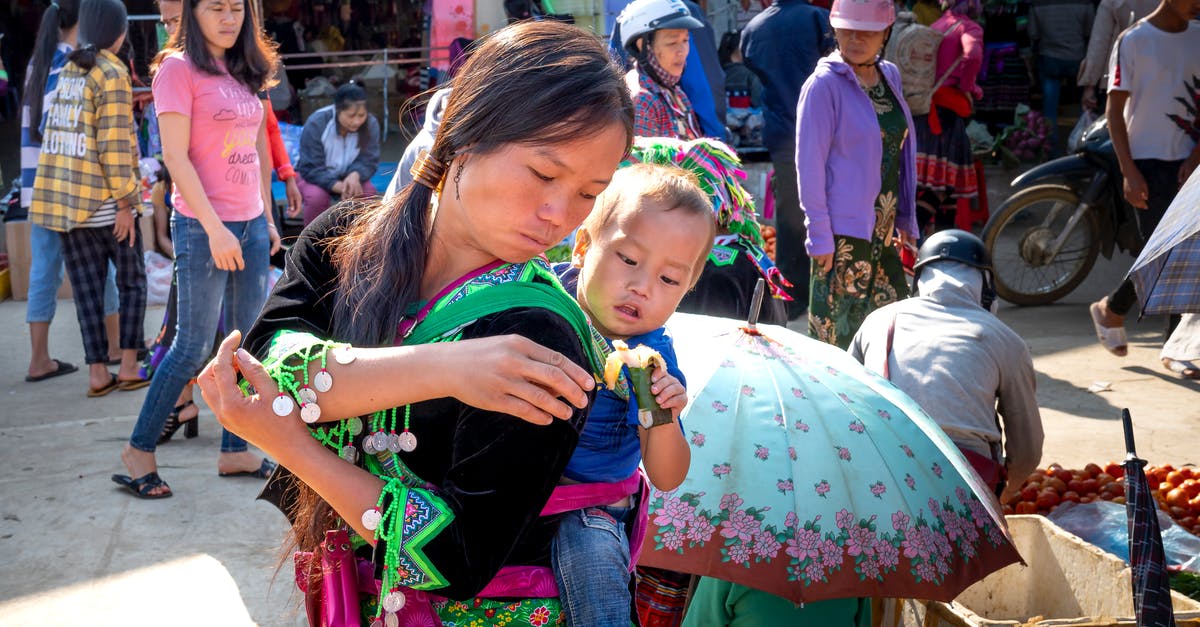 Less sticky rice and lentils - Asian mom carrying baby with sweet rice treat in market