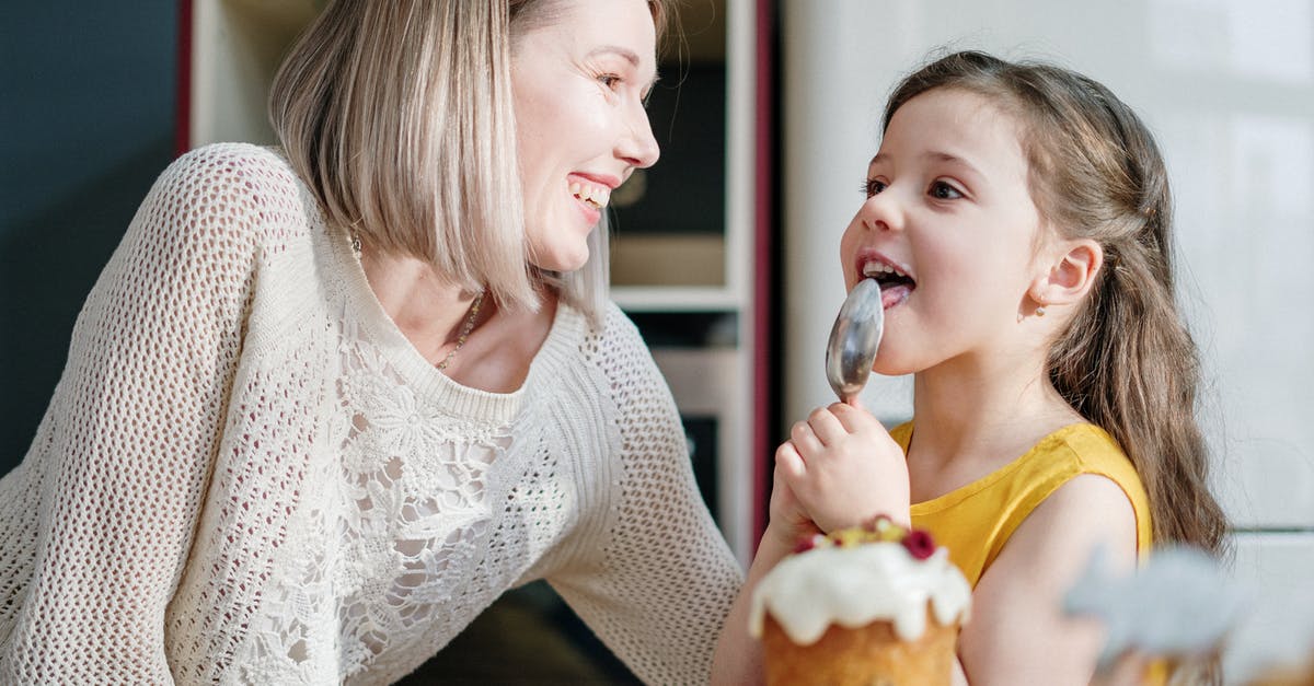 licking spoon and putting back in the food - Woman in White Knit Sweater Smiling while Little Girl Licking Icing on Her Spoon
