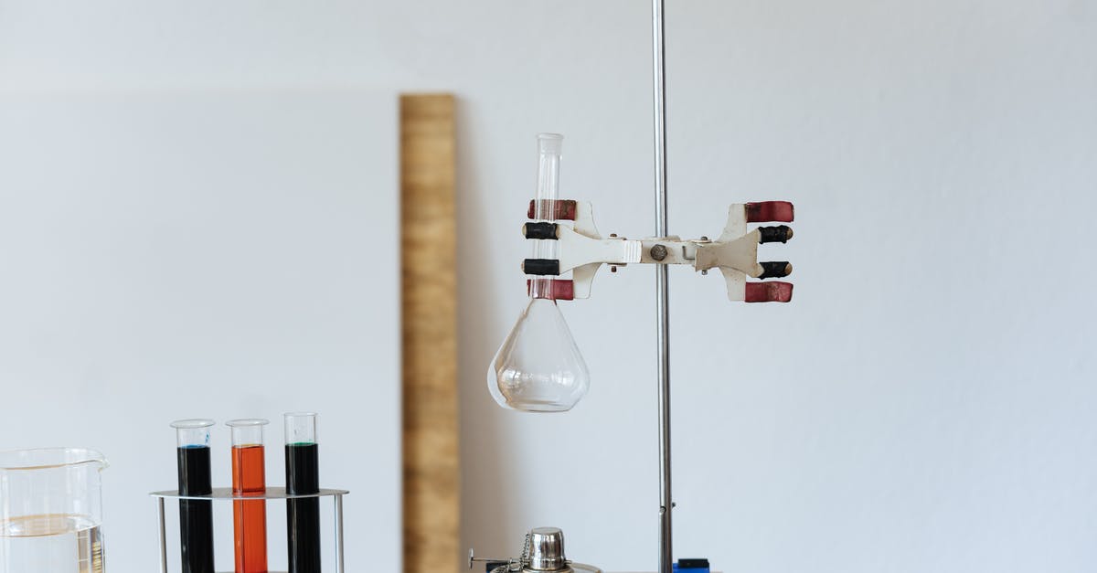 Liquid glucose stuck furniture - Chemical test with empty flask mounted on ring stand while burner under flask and tubes filled with reagents in modern lab