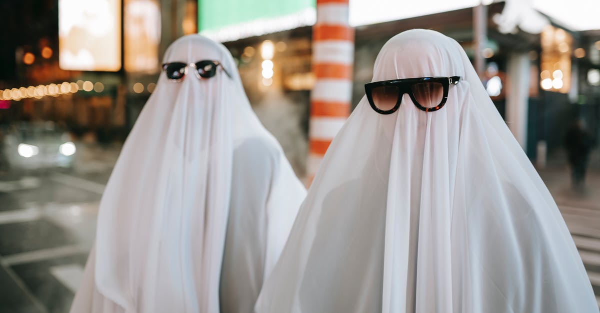 Lobster, steamed Saturday afternoon, eaten Monday night? - Anonymous couple wearing ghost costumes and sunglasses standing on road near steam pipe and glowing signboards on blurred background on street