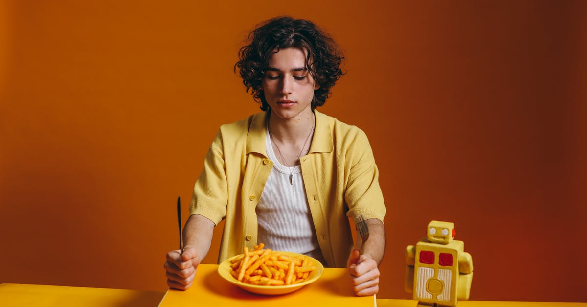 Looking for the name of an orange crunchy snack - Young Man Looking Down On A Plate Of Fries