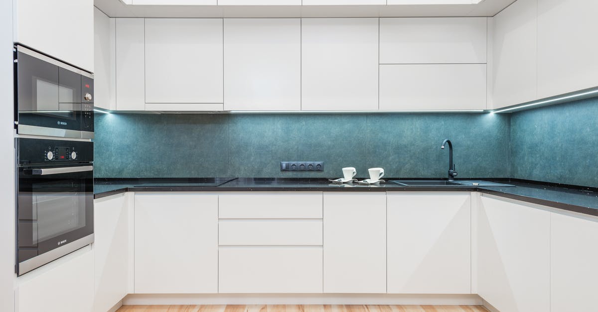 Lysol on microwave, how to clean off? - Interior of white modern kitchen with minimalist design of white cabinets blue backsplash and black built in appliances