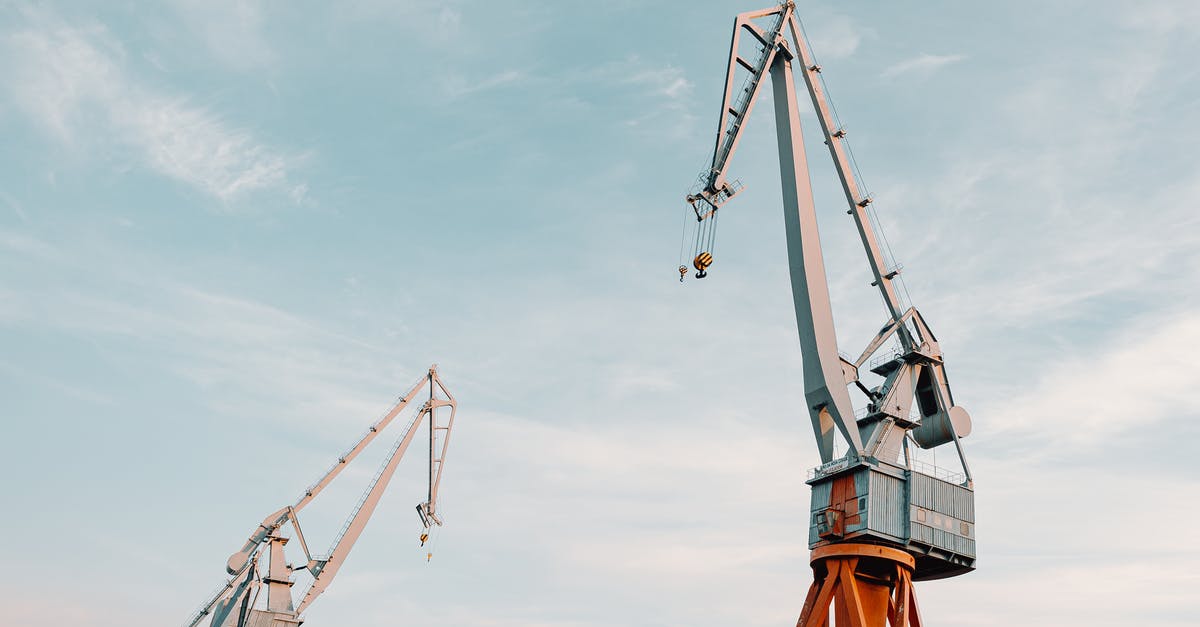 Maintenance and safety of cast iron skillet - From below of metal industrial construction cranes located under clear blue sky on daytime