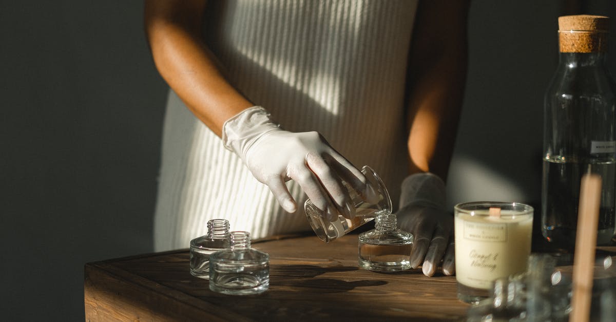 Make catsup more clingy - Unrecognizable crop African American female pouring essential oil in glass bottle while making liquid incense at table