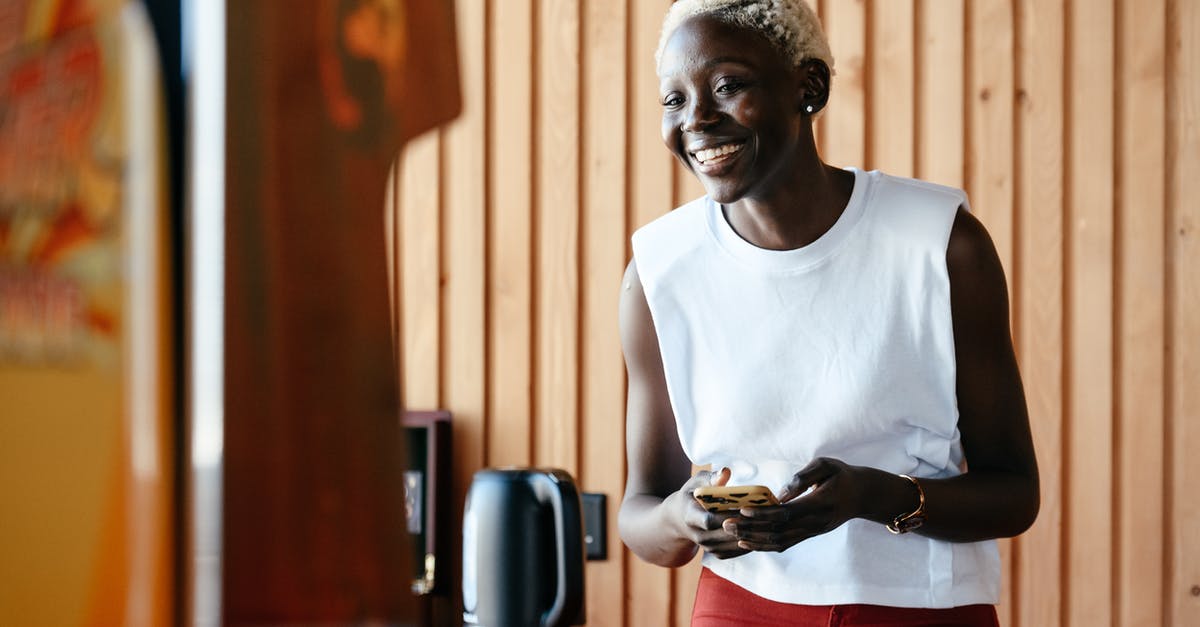 Make espresso in office kitchen- just have a kettle and microwave? - Young happy black woman using smartphone in office kitchen