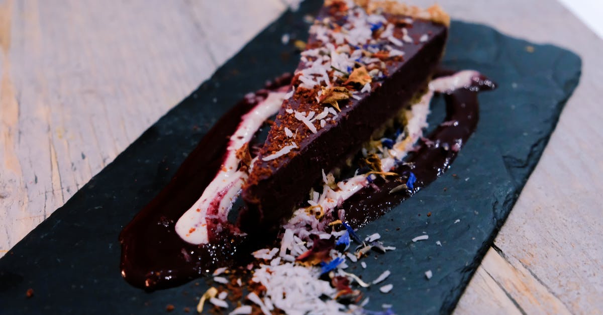 Making a dark, suspended chocolate sauce - Piece of tasty chocolate cheesecake with coconut flakes in cafe