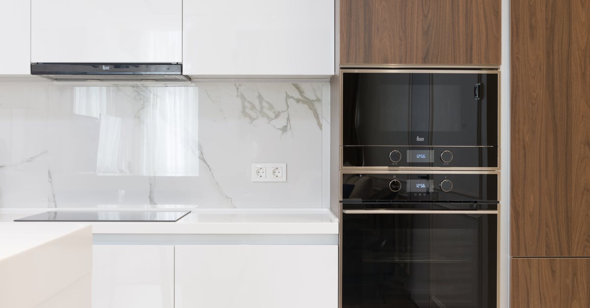 Making black bread in a microwave oven - Modern interior of white and wooden kitchen with cabinets cupboards and built in appliances in contemporary flat