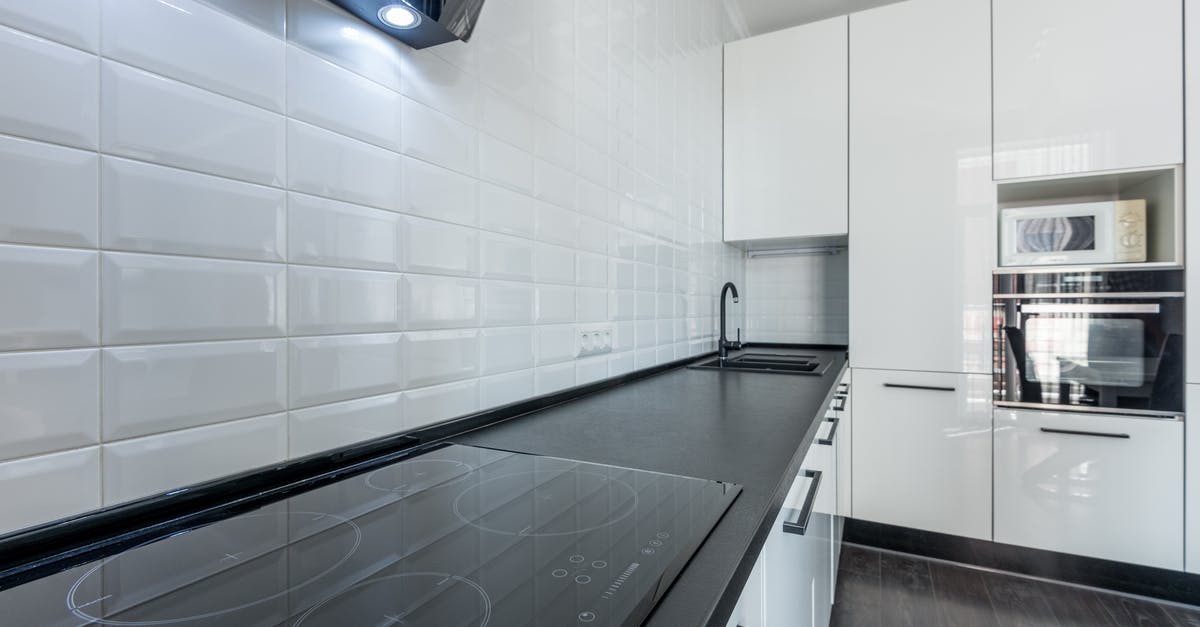 Making black bread in a microwave oven - Interior of modern light white kitchen furnished with white cupboards and appliances with wooden floor and tiled wall