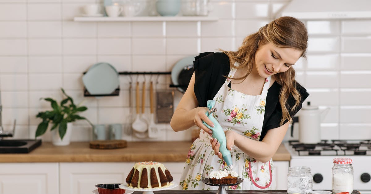 Making cake icing look professionally smooth - Woman in Black Top and Floral Apron in a Kitchen