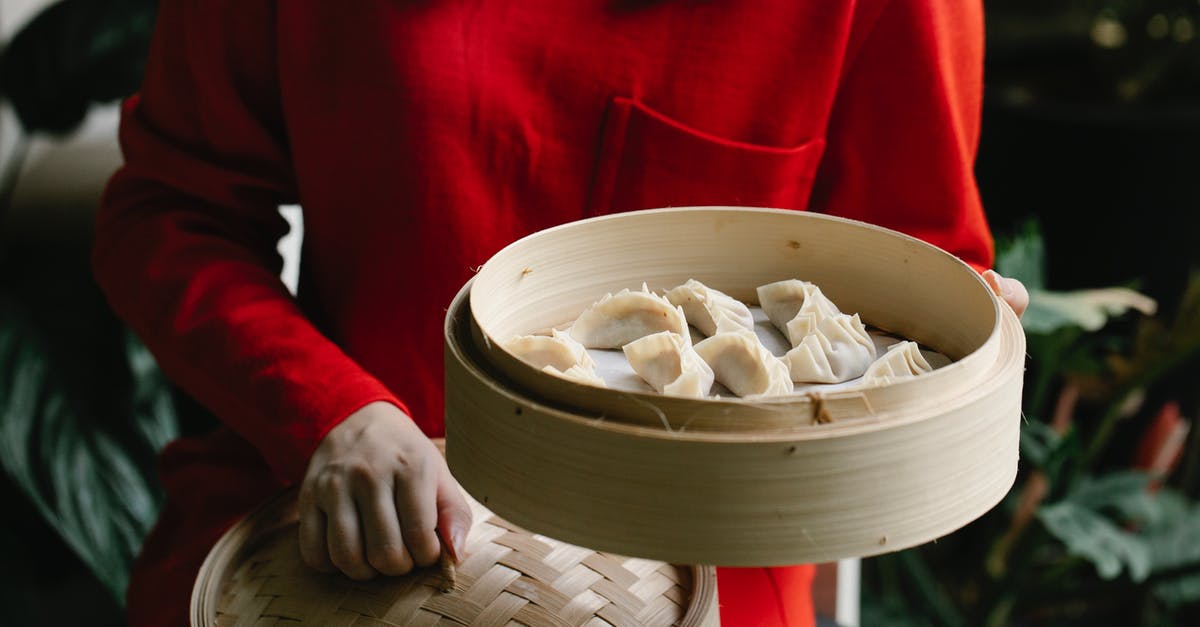 Making dumplings without a snug lid - A Woman in Red Long-Sleeve Shirt Holding a Bamboo Steamer with Dumplings