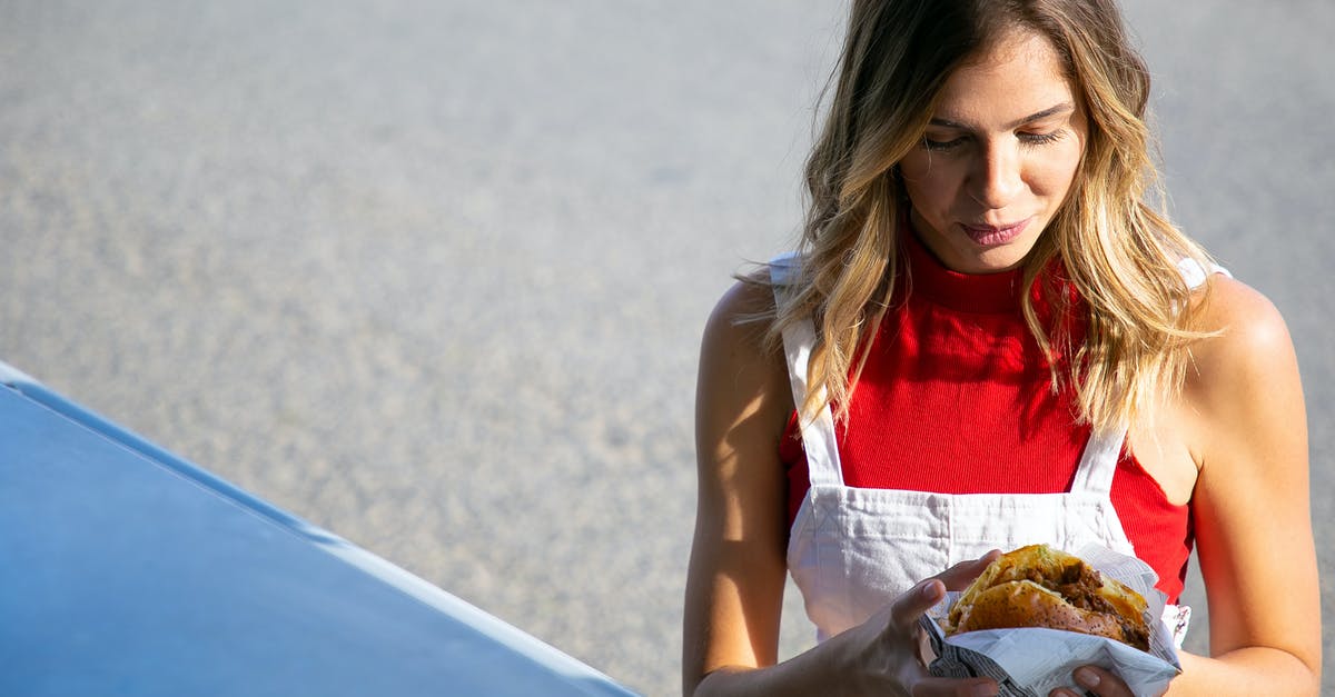 Making fried pickles ahead of time - Young woman with hamburger on street