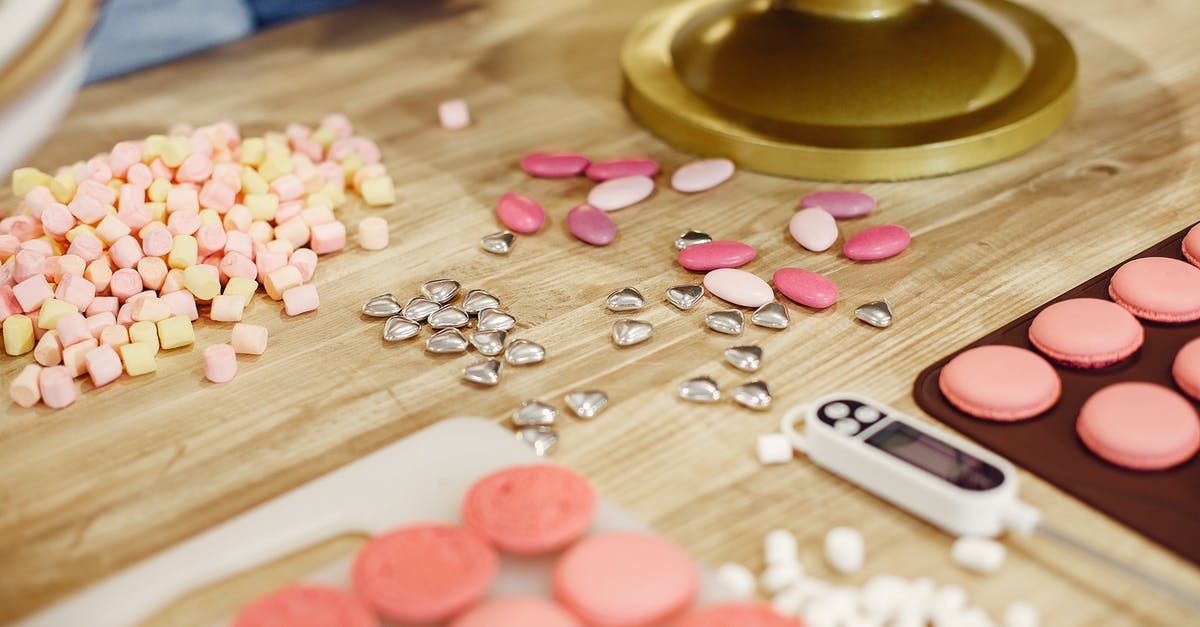 Making Pâté à bombe without sugar thermometer - Table with various shiny sprinkles placed near mat of macaroons and cooking thermometer in process of making delicious desserts in restaurant