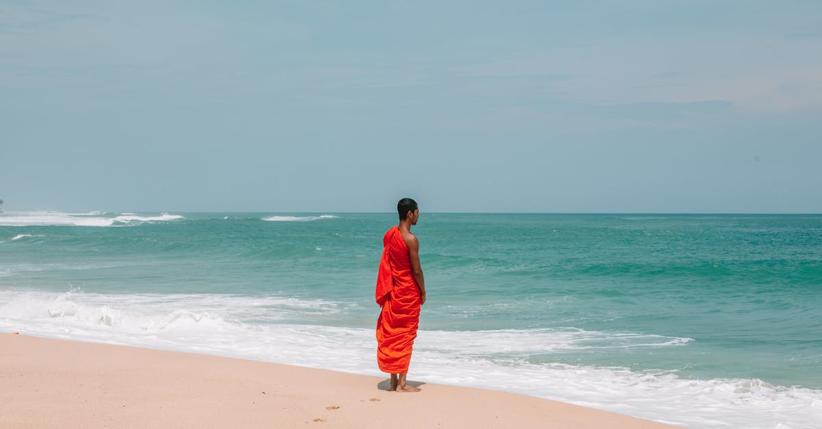 Making sourdough bread in a warm and humid climate - Unrecognizable Asian man in traditional orange cloth on beach