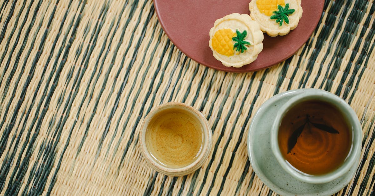 Masking the grass flavor of green tea - From above of oriental cups of green and black tea near plate with yummy crunchy treats on wicker mat