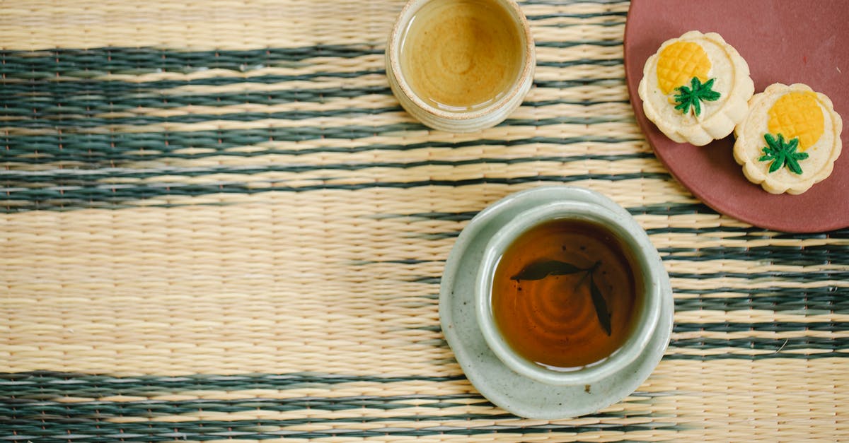 Masking the grass flavor of green tea - High angle of aromatic black and green tea in ceramic Asian cups near plate with delicious pastries on table