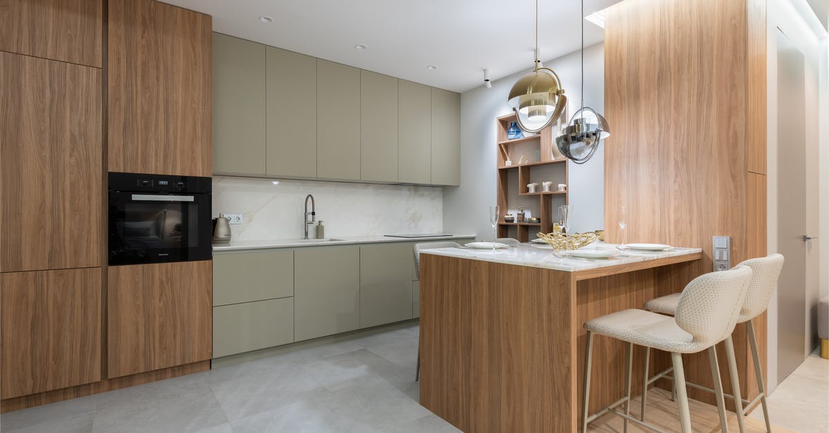 Maximum oven temperature for glass cookware - Interior of bright modern kitchen with cupboards near chairs with counter decorated with glasses and plates under lamps next to shelves on wall