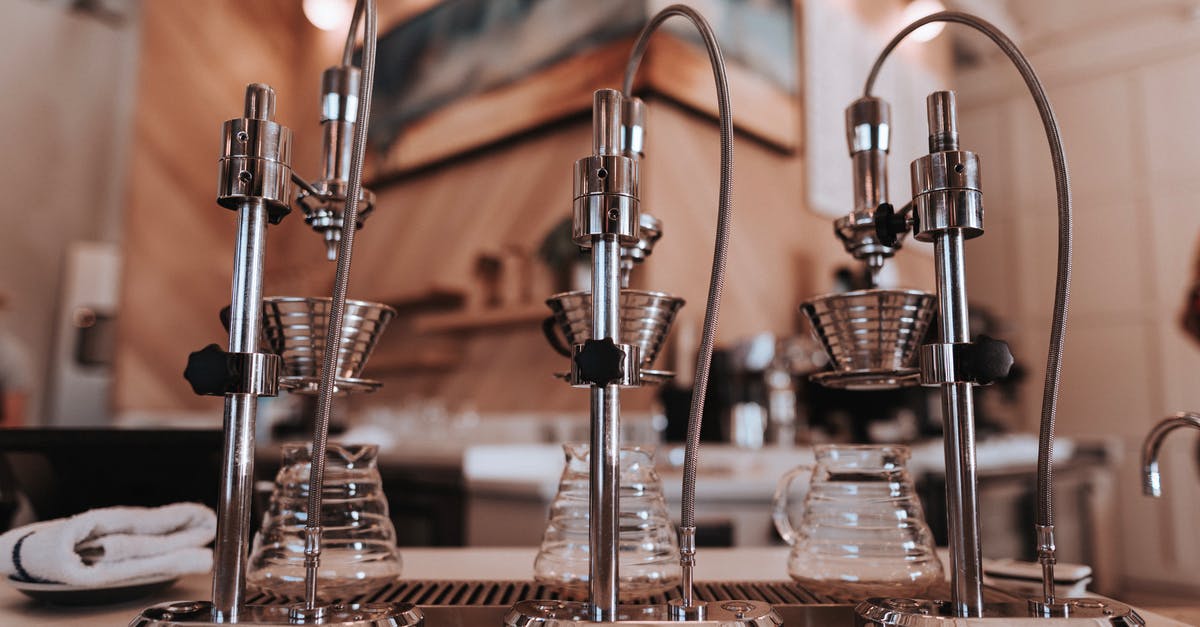 Method of sharpening knives with steel - Stainless steel similar drip coffee machine with ribbed filters and transparent glass carafes on table near towel in apartment with artificial light