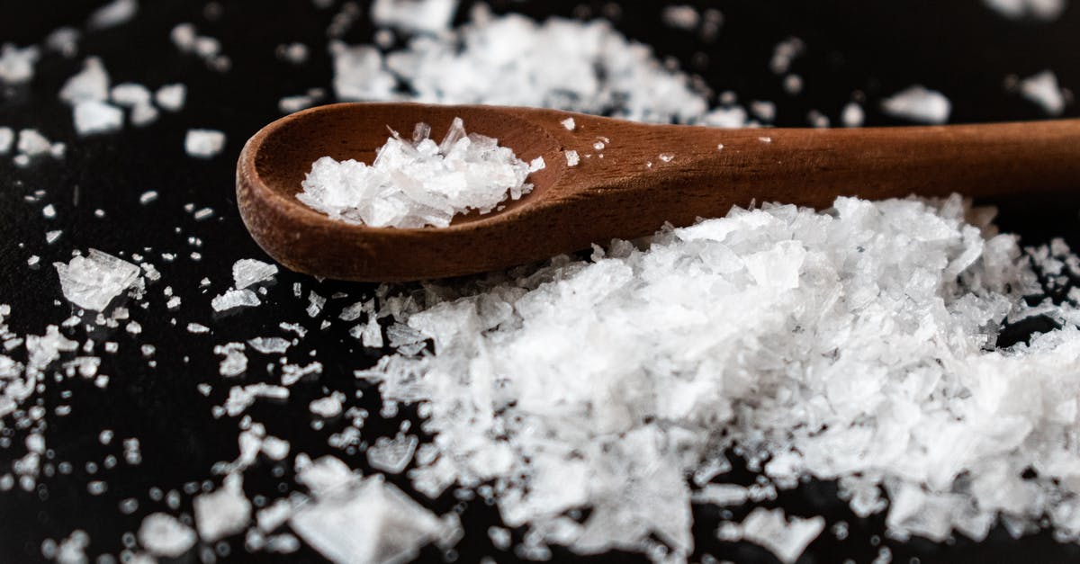 Methods for seasoning wooden spoons? - Closeup of wooden spoon arranged with sea salt scattered on table in kitchen